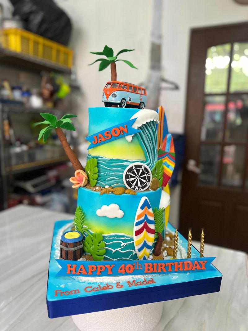 Two-tier beach-themed 40th birthday cake with surfboards, palm trees, a wave and a vintage van topper