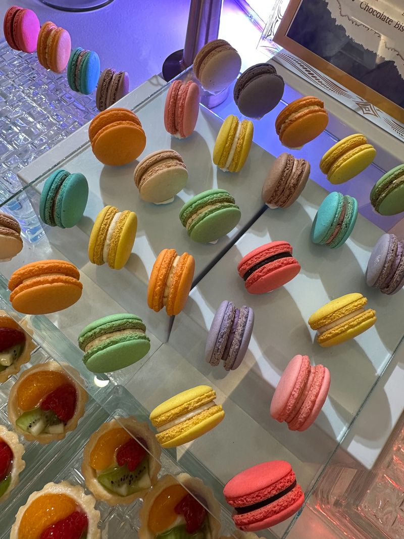 Rainbow-colored French macarons standing in rows on an acrylic display
